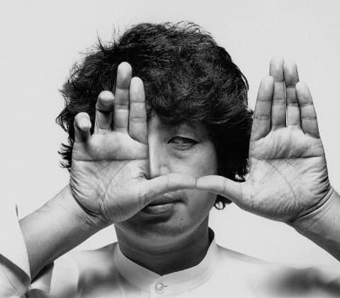 A portrait of Shiro Kuramata with hands gesturing a frame in front of their face